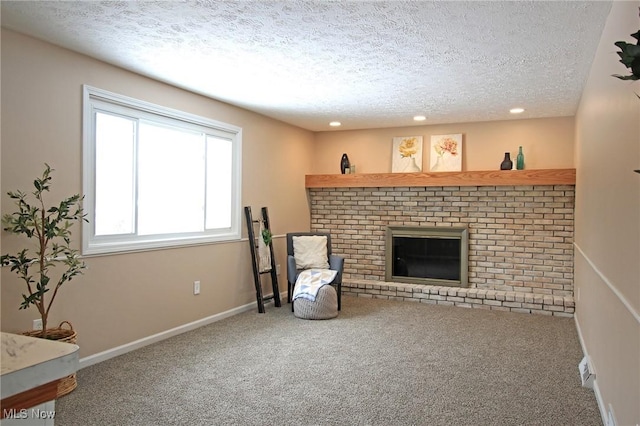 living area featuring carpet floors, a brick fireplace, a textured ceiling, and baseboards