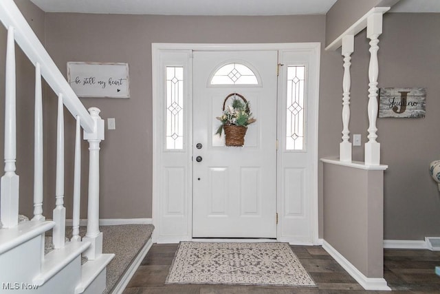 foyer entrance featuring dark wood-style floors, baseboards, and stairway