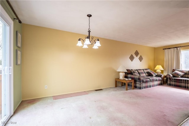 living room featuring carpet floors, baseboards, and an inviting chandelier