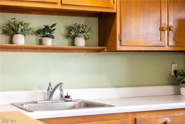 kitchen with brown cabinetry, light countertops, and a sink