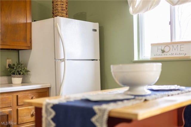 kitchen featuring light countertops, brown cabinetry, and freestanding refrigerator