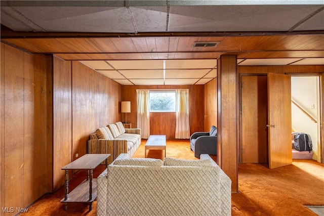 carpeted living area featuring wooden walls and visible vents