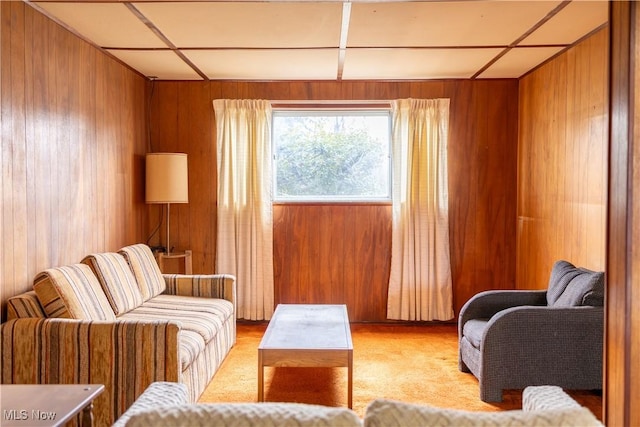 sitting room with light carpet and wood walls