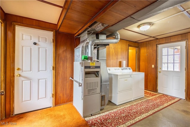 laundry area featuring laundry area, wood walls, washing machine and clothes dryer, and heating unit