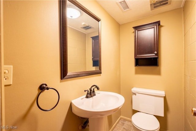 bathroom featuring toilet, baseboards, visible vents, and a sink