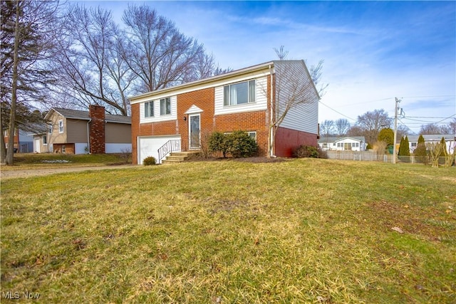 split foyer home with an attached garage, brick siding, fence, and a front yard