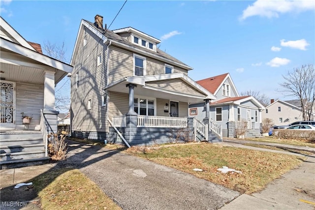 american foursquare style home with covered porch, a chimney, and a residential view