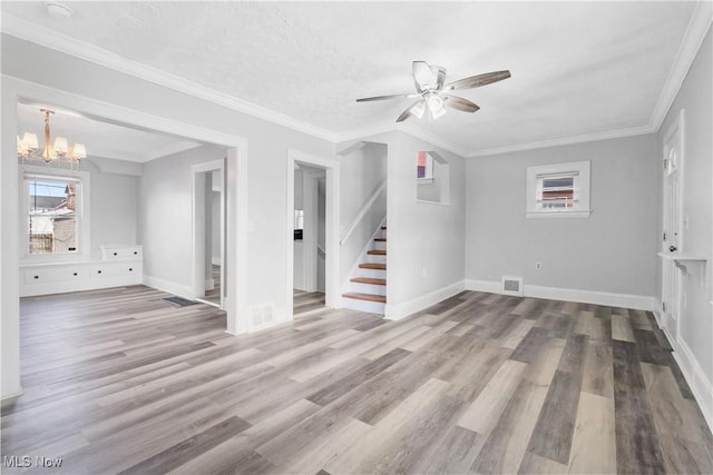 unfurnished room featuring visible vents, stairway, ornamental molding, wood finished floors, and baseboards