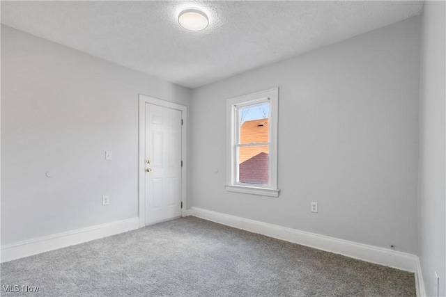 unfurnished room featuring carpet, a textured ceiling, and baseboards