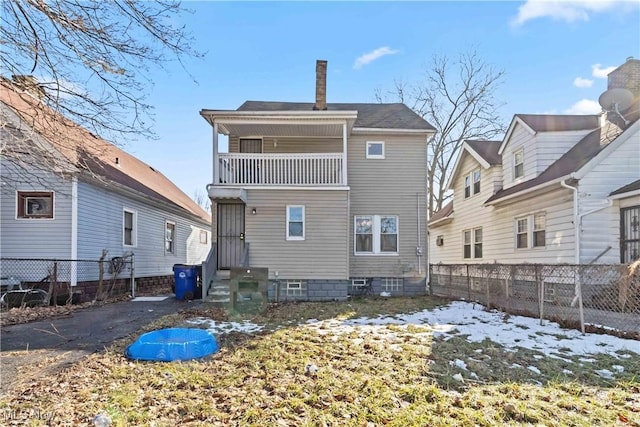 snow covered property featuring entry steps, a chimney, fence, and a balcony