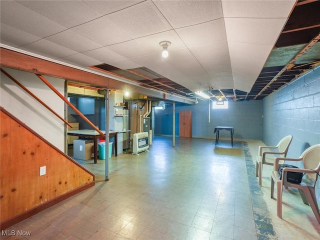 below grade area with concrete block wall, heating unit, stairs, and tile patterned floors