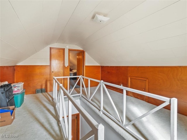 additional living space featuring vaulted ceiling, carpet floors, and wood walls