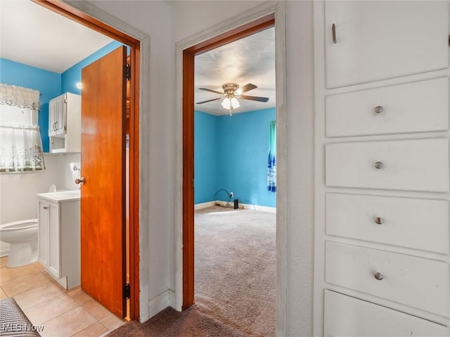 hallway with light colored carpet, baseboards, and light tile patterned flooring