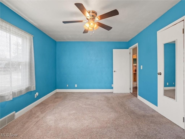 unfurnished room featuring carpet floors, baseboards, visible vents, and a ceiling fan