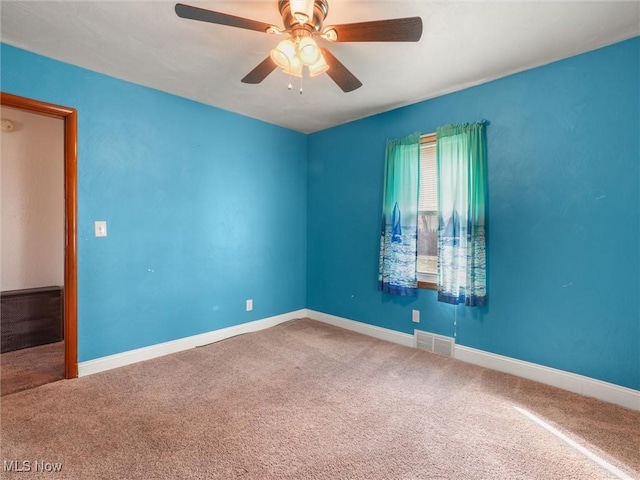 empty room with baseboards, visible vents, ceiling fan, and carpet flooring