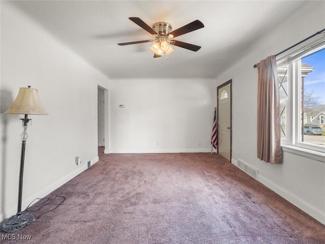 carpeted empty room featuring a ceiling fan, visible vents, and baseboards