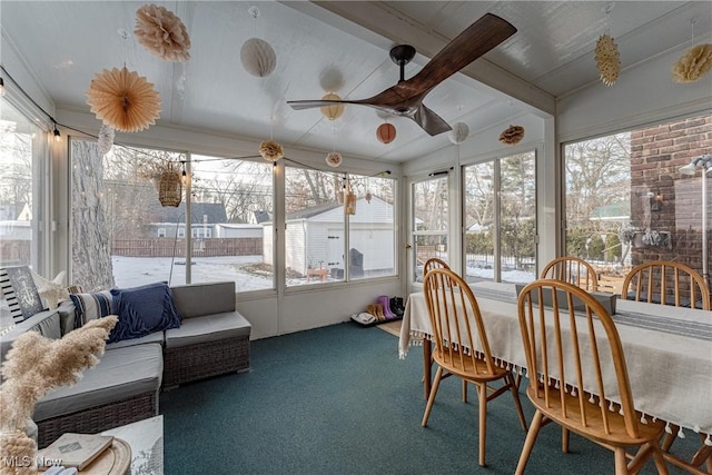 sunroom with lofted ceiling with beams and a ceiling fan