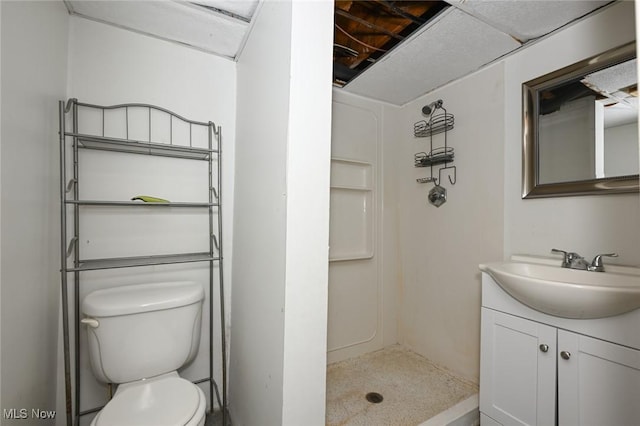 bathroom featuring toilet, walk in shower, a drop ceiling, and vanity