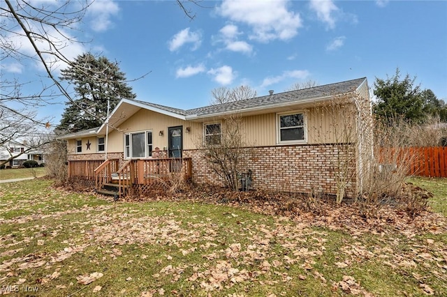 back of property with brick siding and a lawn