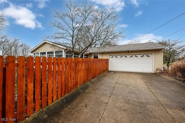 exterior space featuring roof with shingles, fence, and a detached garage