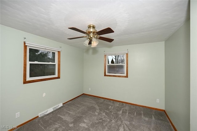 carpeted empty room featuring ceiling fan, visible vents, and baseboards