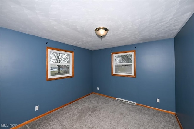 empty room with baseboards, a textured ceiling, visible vents, and carpet flooring