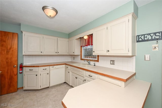 kitchen featuring tasteful backsplash, light countertops, white cabinetry, a sink, and dishwasher