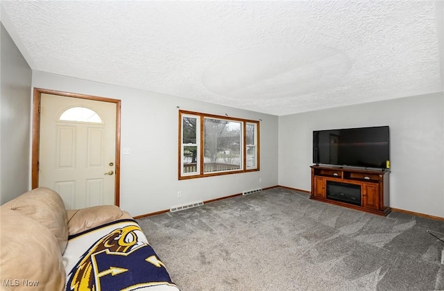 carpeted living area with a textured ceiling, visible vents, and baseboards