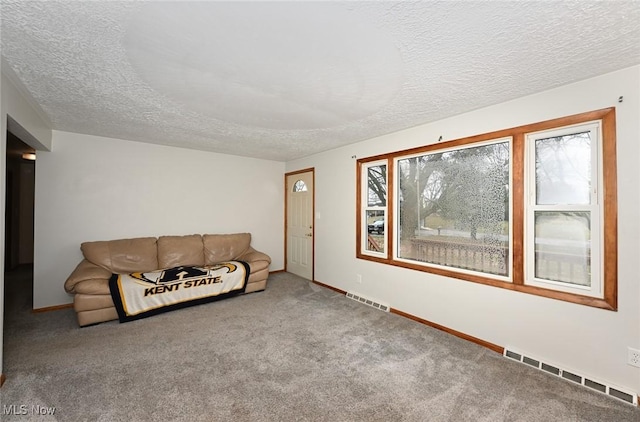 unfurnished living room with a textured ceiling, carpet, visible vents, and baseboards