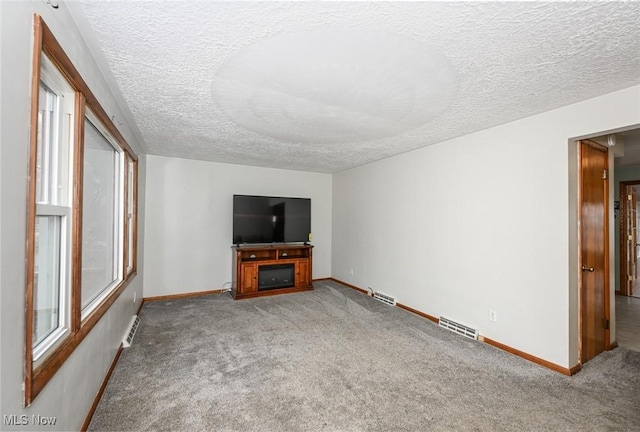 unfurnished living room with carpet floors, visible vents, and baseboards