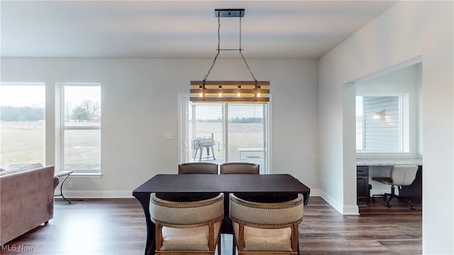 dining area with baseboards, dark wood finished floors, built in study area, and a healthy amount of sunlight