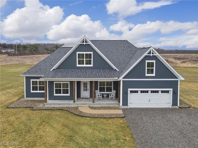 view of front of property with gravel driveway, covered porch, a shingled roof, and a garage