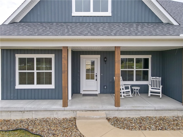 view of exterior entry featuring a porch and roof with shingles