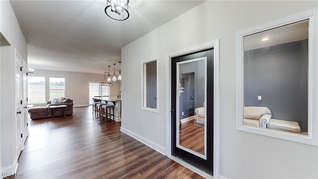 corridor featuring dark wood-type flooring and baseboards