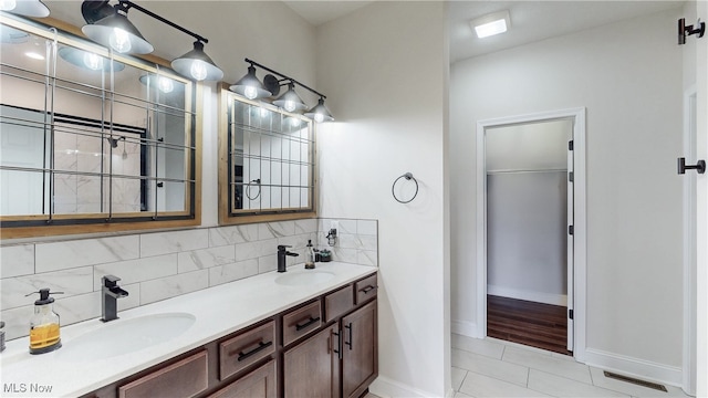 full bath featuring visible vents, a sink, backsplash, and double vanity