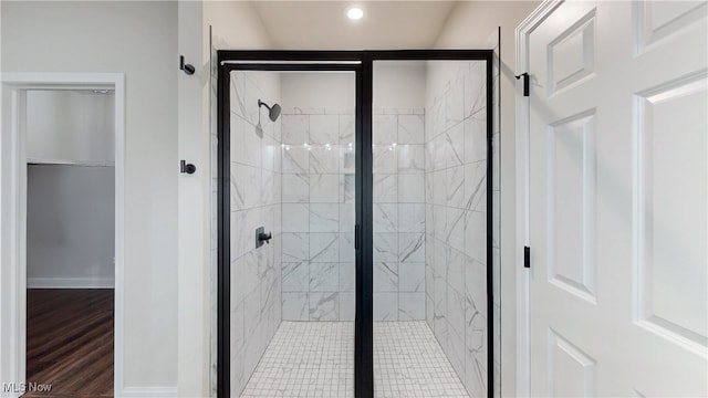 bathroom with a stall shower, baseboards, and wood finished floors