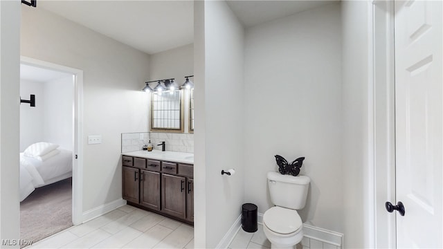 ensuite bathroom with toilet, decorative backsplash, connected bathroom, vanity, and baseboards