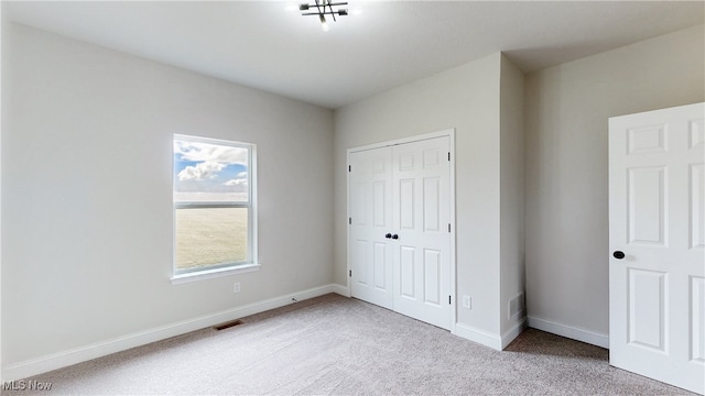 unfurnished bedroom featuring light carpet, baseboards, visible vents, and a closet