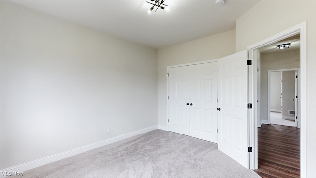 unfurnished bedroom featuring a closet, light carpet, and baseboards