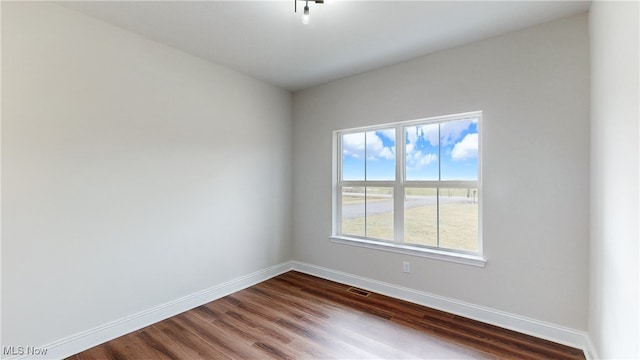 unfurnished room featuring visible vents, baseboards, and wood finished floors