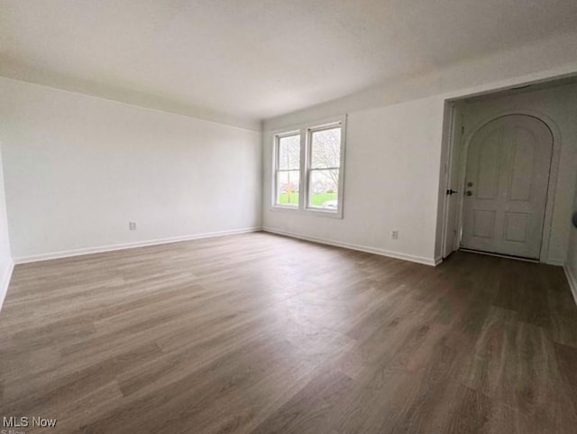 empty room with dark wood-type flooring and baseboards