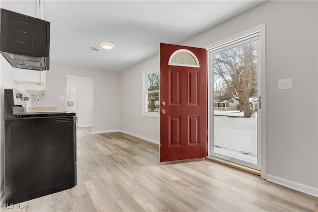 entrance foyer with light wood-type flooring, a healthy amount of sunlight, and baseboards