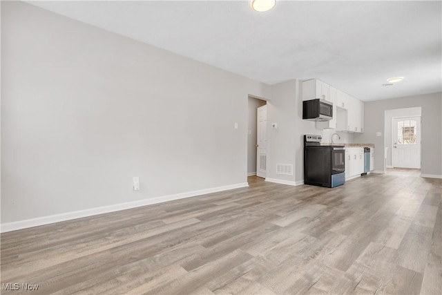 unfurnished living room with visible vents, light wood-style flooring, and baseboards