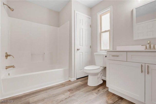 bathroom featuring toilet, vanity, wood finished floors, and shower / tub combination