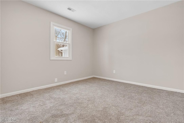 unfurnished room with carpet, visible vents, and baseboards