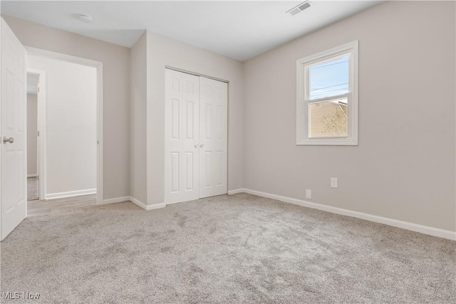 unfurnished bedroom featuring light carpet, baseboards, visible vents, and a closet