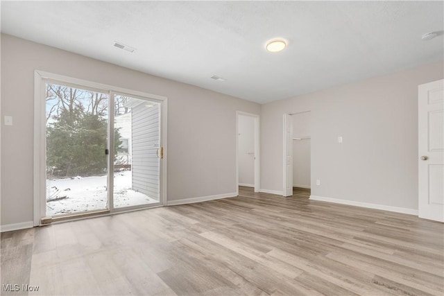 unfurnished room featuring visible vents, light wood-style flooring, and baseboards