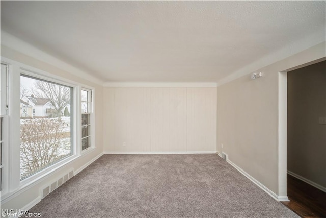 carpeted spare room with visible vents and baseboards