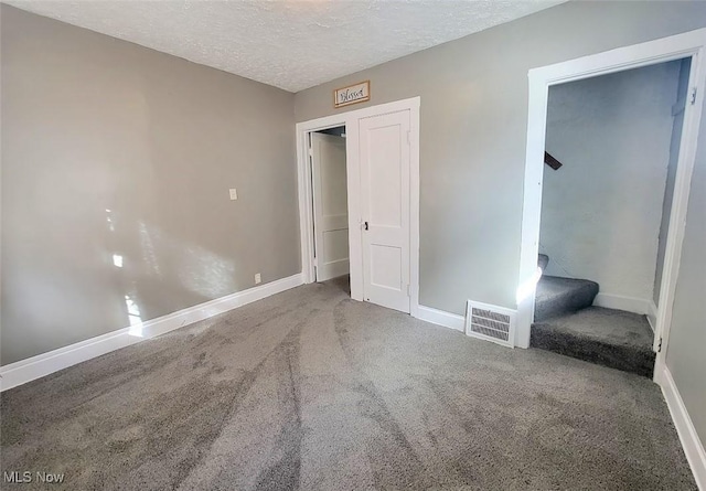 unfurnished bedroom with carpet floors, baseboards, visible vents, and a textured ceiling