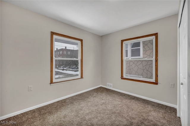 carpeted spare room featuring baseboards and visible vents